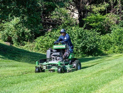 Man Cutting Grass In Summer With A Standing Lawn Mower