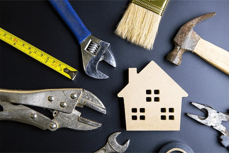 construction tools surrounding a wooden toy house in a circle