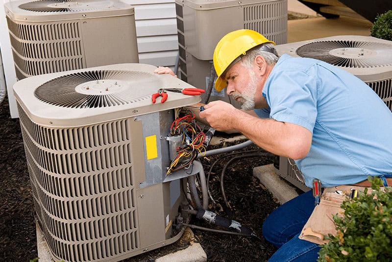 repairman working on an outdoor air conditioning unit